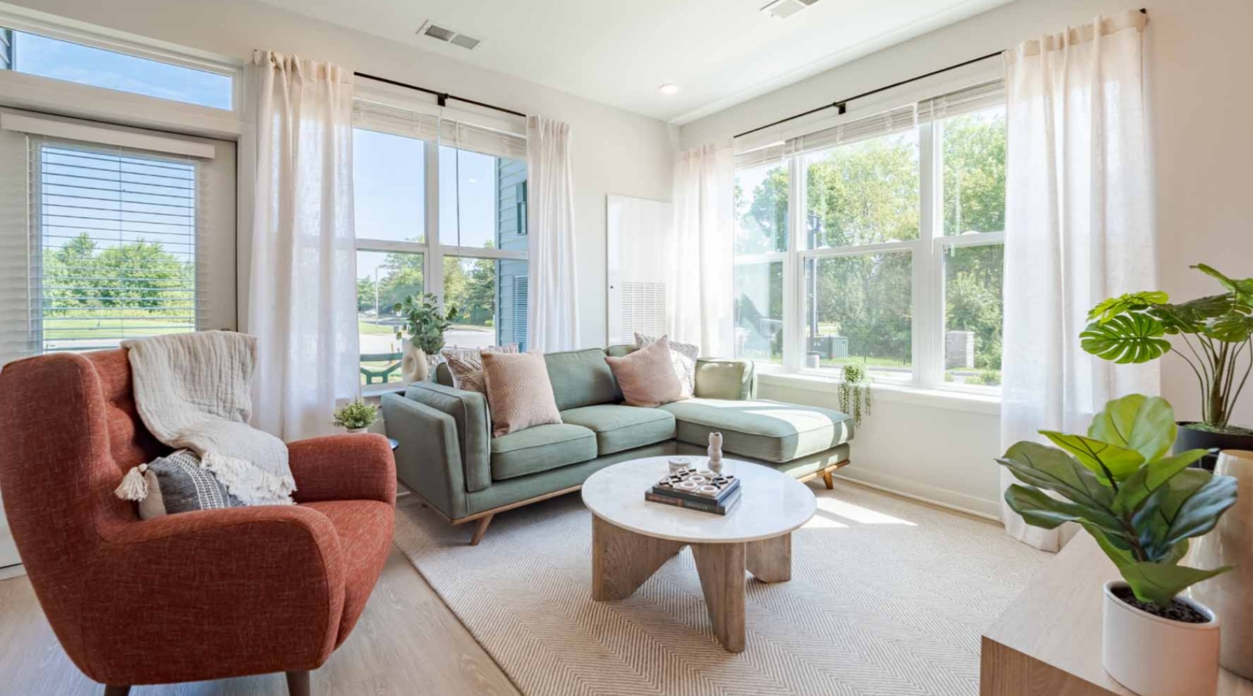 Artfully crafted 1, 2, and 3 bedroom apartments in Burlington living room couch, chairs and table by the window  J Centra Burlington NJ luxury apartments
