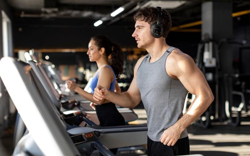 a man wearing headphones and woman running on treadmill in gym  J Centra Burlington NJ apts for rent 